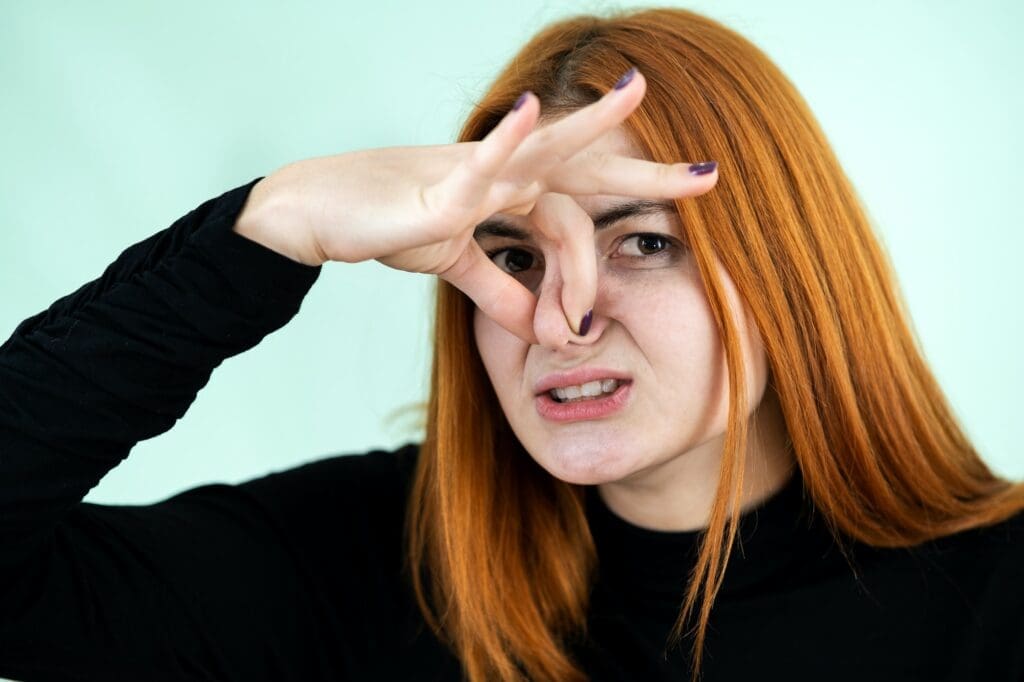 Funny pretty redhead girl showing bad water damage smell sign with her fingers